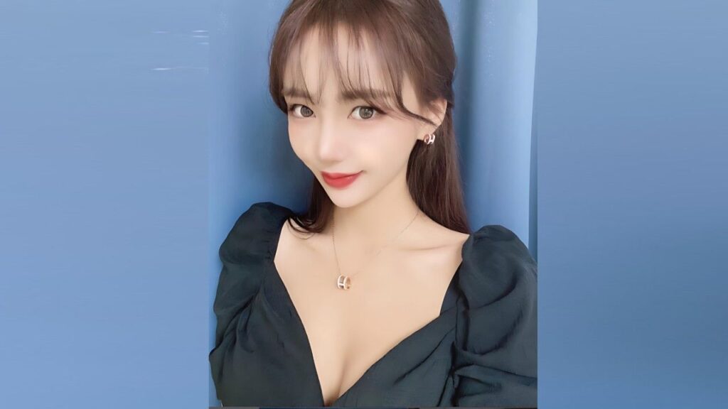 Seo Yoon-ah with long dark hair in a green puff-sleeve top, smiling softly against a blue backdrop, wearing a pendant.
