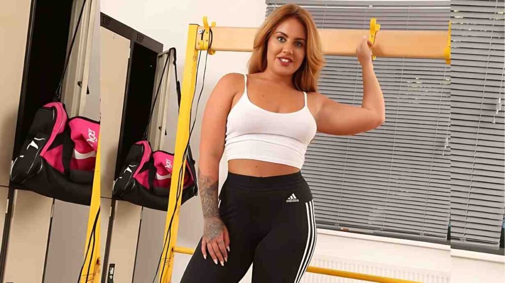 Alexa B in white sports bra and black Adidas leggings poses beside a yellow gym rack with bands.