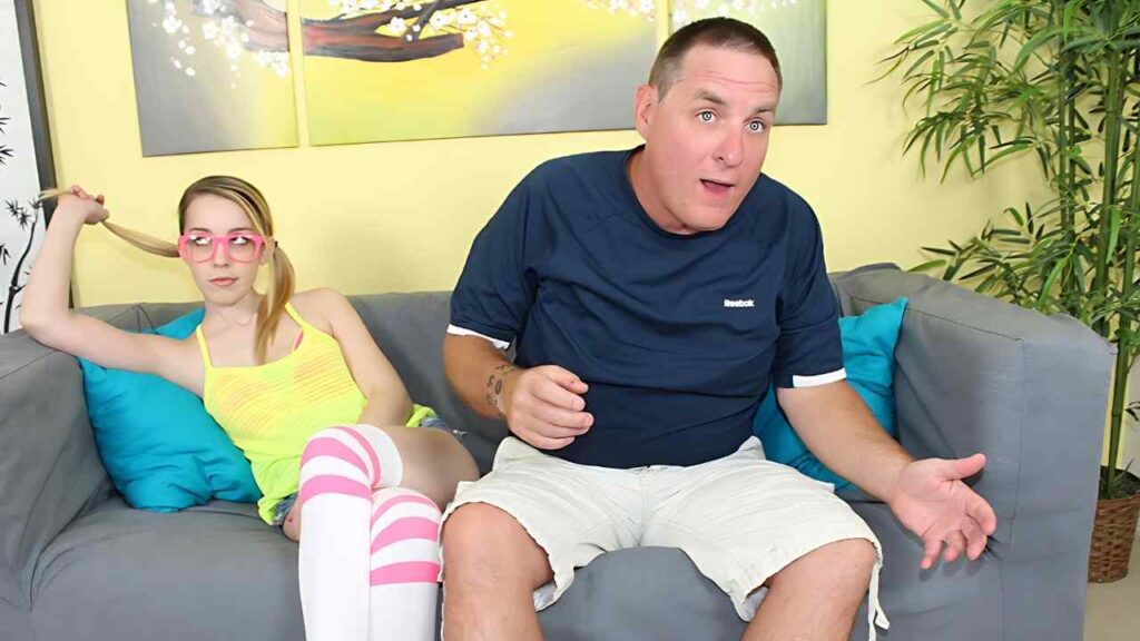 Joe Hardick in a navy shirt gestures as a woman in neon yellow top and pink striped socks twirls her hair.