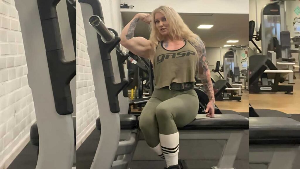 Marika Johansson in an olive top and green leggings sits on a gym bench beside cardio machines, flexing her bicep; tattooed arms.