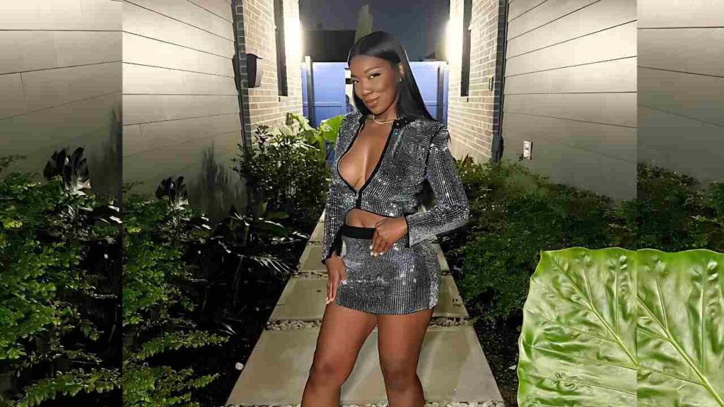 Megan B in a silver sequin cropped jacket and matching mini skirt, posing with black hair.