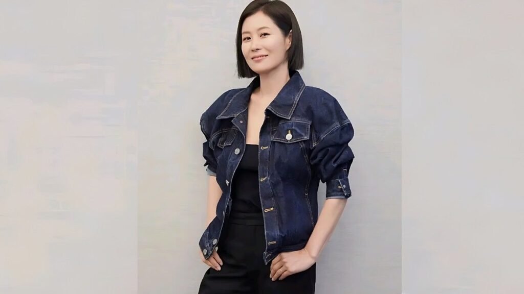 Moon So-ri with a bob wears an oversized denim jacket over a black top, standing with hands on hips against a pale wall.