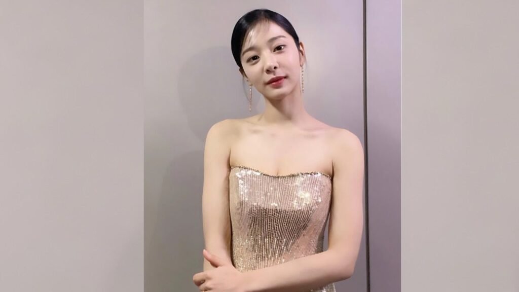 Seol In-ah with dark hair in a strapless champagne sequined gown, dangling earrings, posing against a neutral wall.