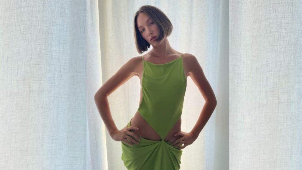 Ava Michelle in a green dress poses confidently for a photo, smiling at the camera.