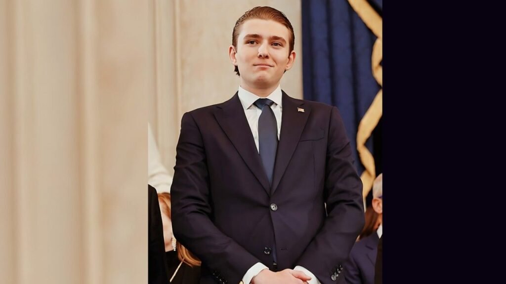 Barron Trump in a suit and tie stands confidently at a podium, preparing to deliver a speech.