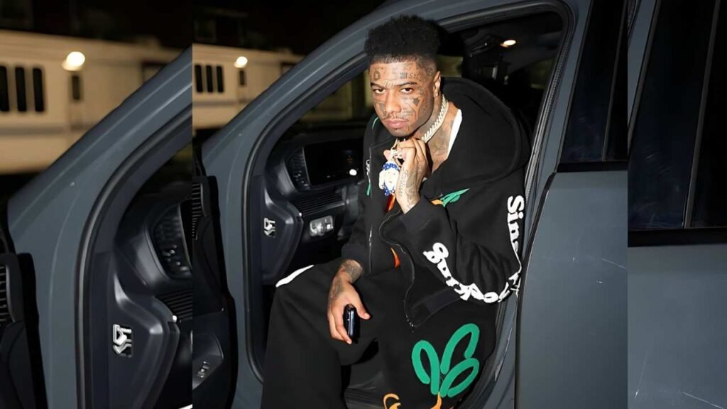 Blueface seated in the back seat of a car, looking out the window with a thoughtful expression.