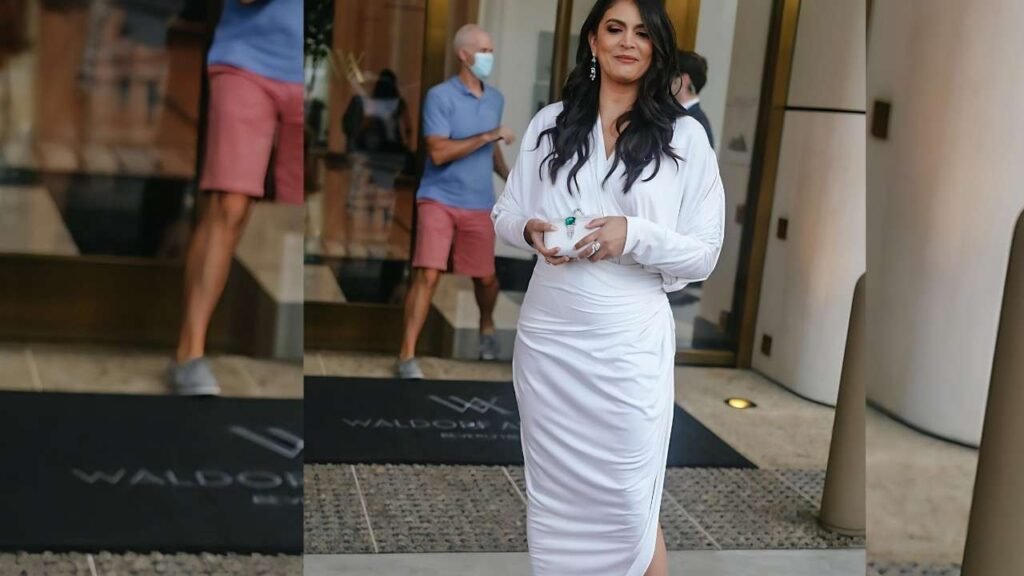 Cecily Strong wearing a white dress and sandals stands gracefully, showcasing a relaxed summer style.
