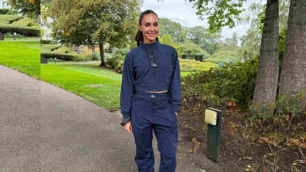 Charley Hull wearing a blue top and pants stands confidently on a path surrounded by greenery.