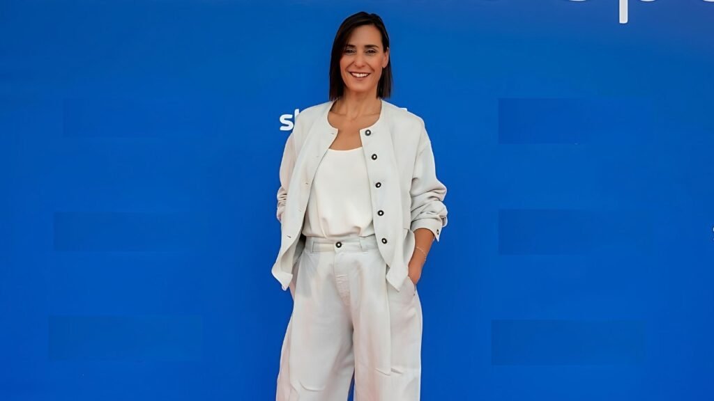 Flavia Pennetta dressed in white pants and a jacket stands at an event, exuding elegance and poise.