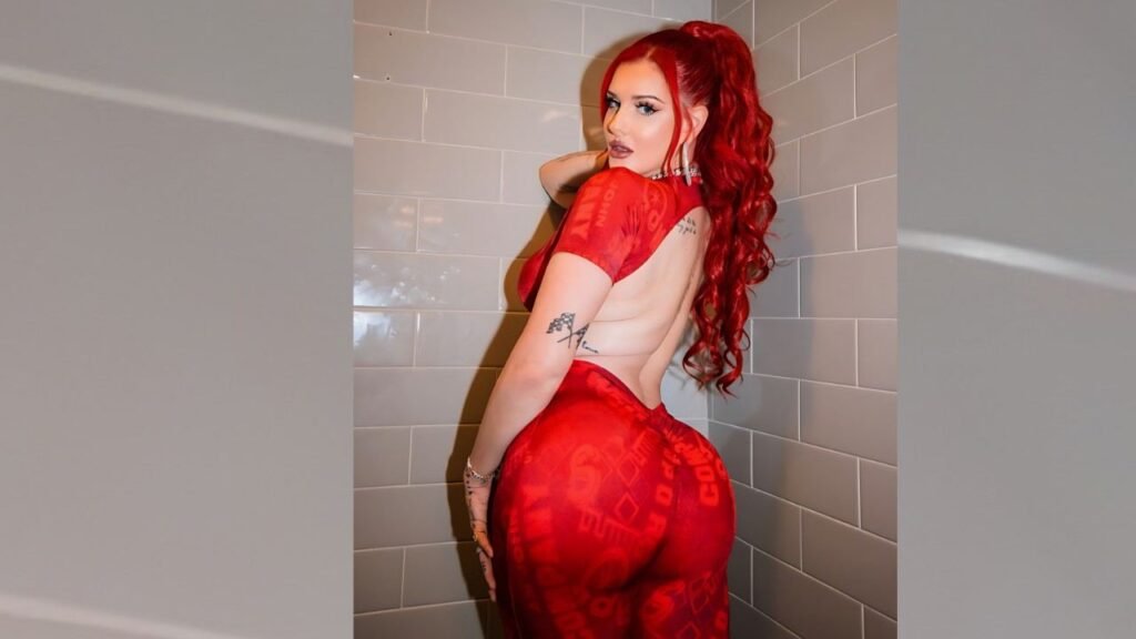 Justina Valentine with red hair poses confidently in a stylish bathroom, showcasing modern decor and bright lighting.