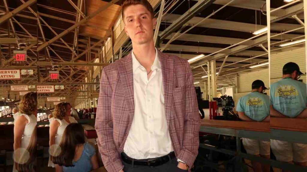 Kevin Huerter in a suit stands confidently in a spacious, modern building with large windows and an open layout.