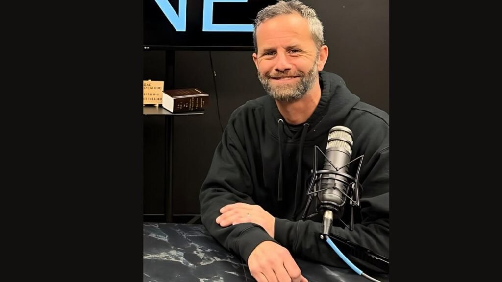 Kirk Cameron seated in front of a microphone, preparing to speak or record audio