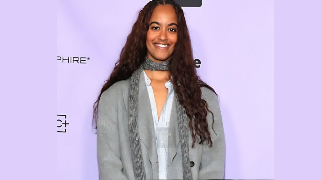 Malia Ann Obama with long hair and a scarf displays a cheerful smile, creating a friendly atmosphere.