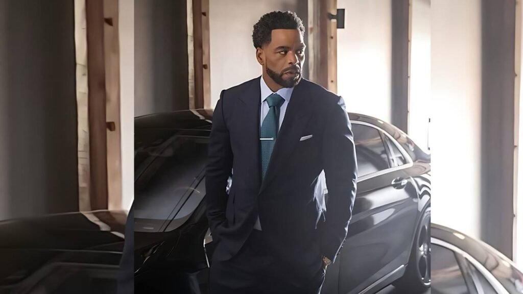Method Man in a formal suit stands beside a luxury car, showcasing a professional appearance and stylish vehicle.