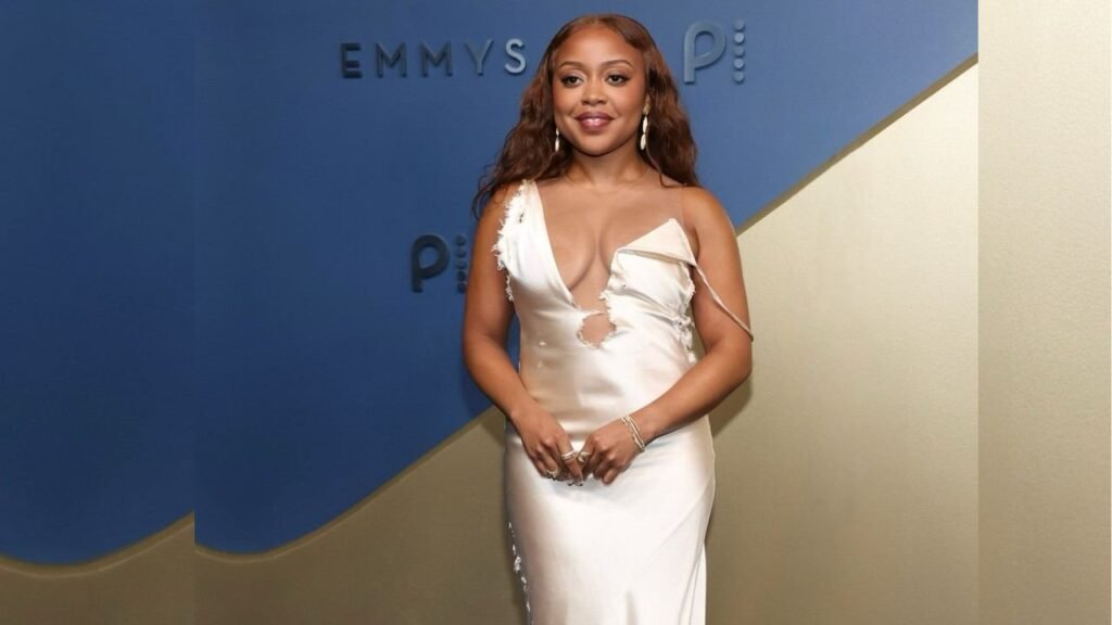 Quinta Brunson poses on the red carpet at the Emmys, wearing an elegant gown and smiling for the cameras.
