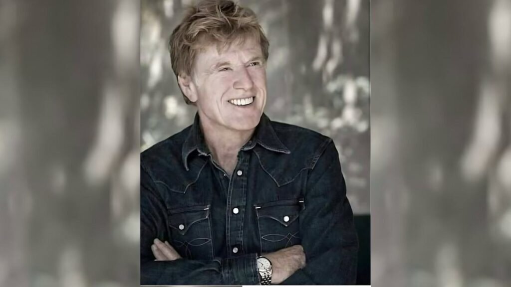 Robert Redford wearing a black shirt smiles warmly at the camera