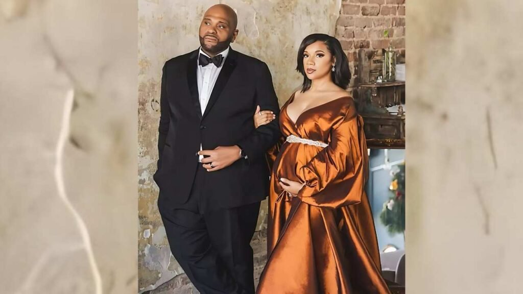 Ruben Studdard and her wife joyfully holding a baby onesie, celebrating their anticipation of becoming parents for the first time.