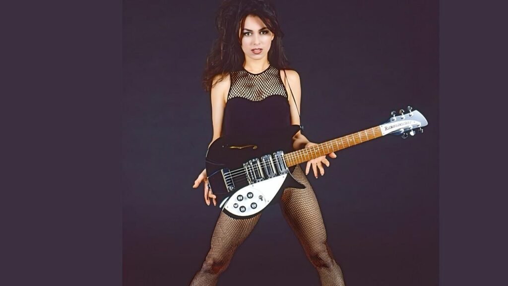 Susanna Hoffs Dark-haired guitarist in a black fishnet bodysuit, posing with a black-and-white Rickenbacker electric guitar.