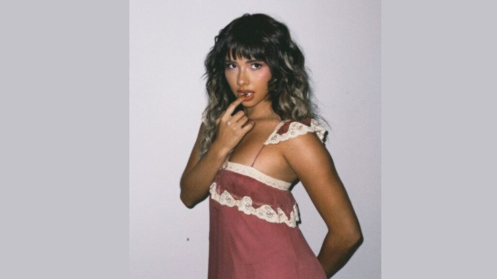 Xochitl Gomez in a pink dress poses confidently for a photo, smiling at the camera.