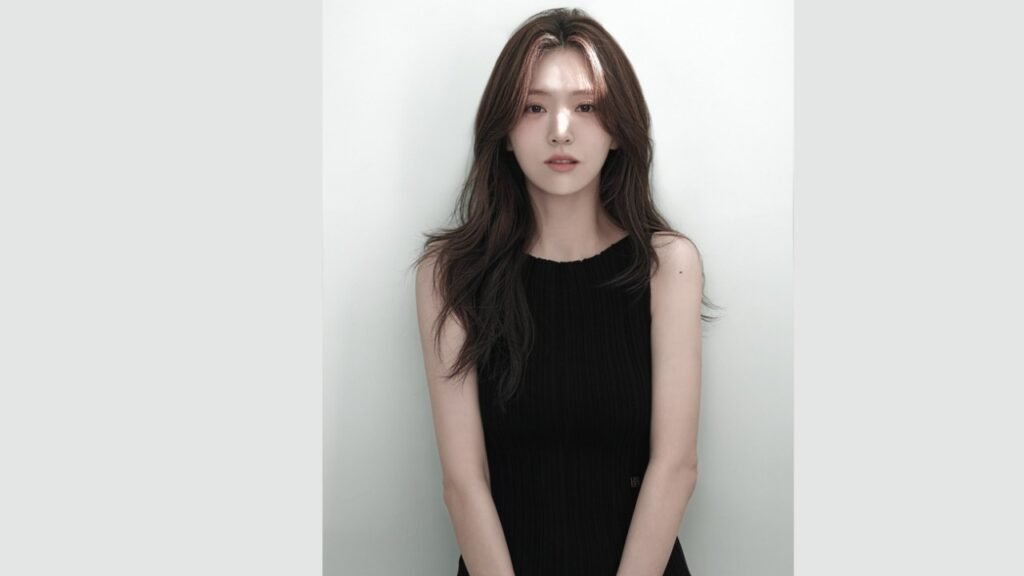 Kim Ji-eun with long hair wearing a black dress stands elegantly, showcasing her style and poise.