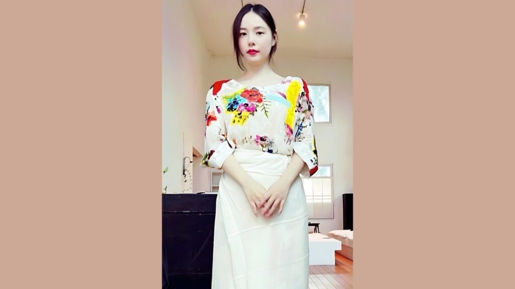Min Hyo-rin wearing a floral top and skirt stands confidently, showcasing a vibrant and stylish outfit
